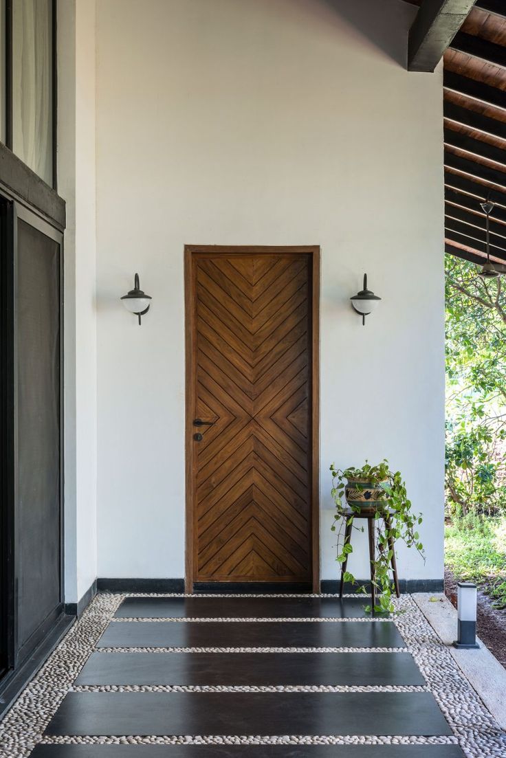 a wooden door sitting on the side of a white wall next to a potted plant