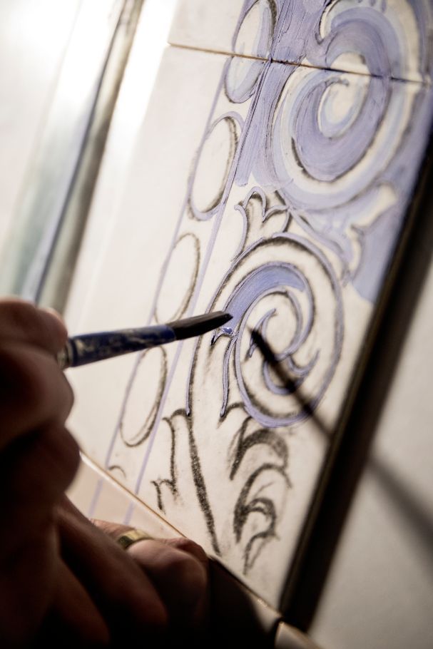 a person is using a pair of scissors to paint a tile design on the wall