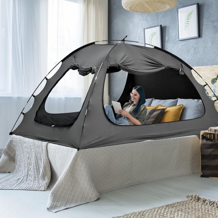 a woman sitting in a tent on top of a bed