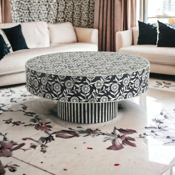 a living room with white couches and black and white patterned coffee table in the middle