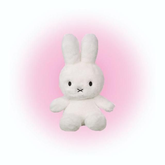 a white stuffed rabbit sitting up against a pink background