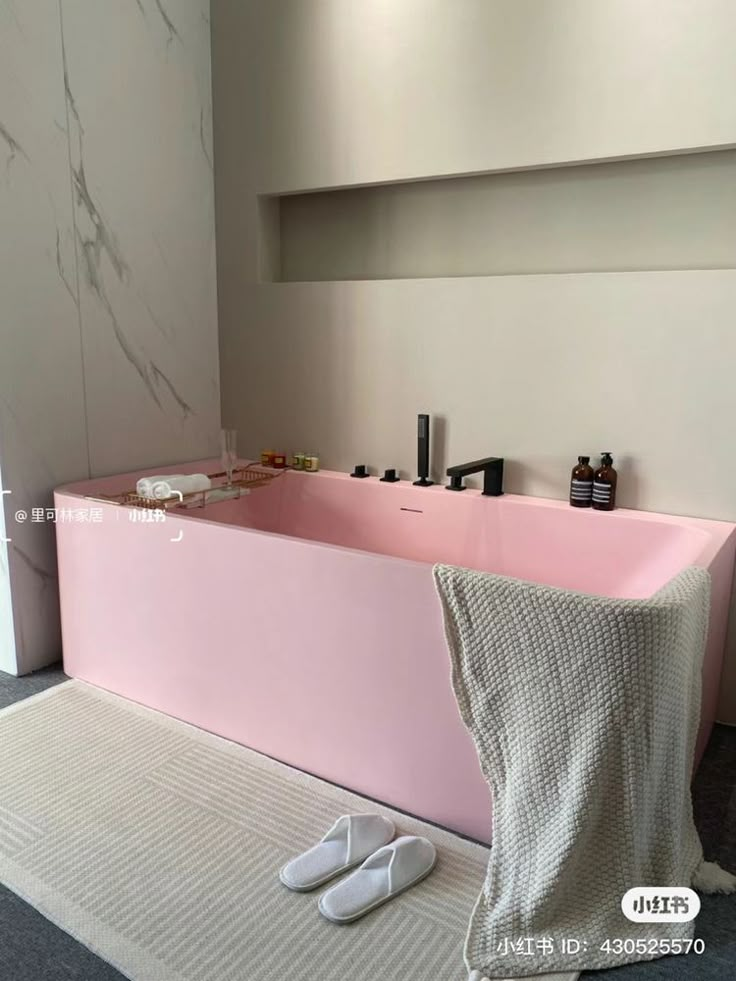 a pink bath tub sitting next to a pair of slippers