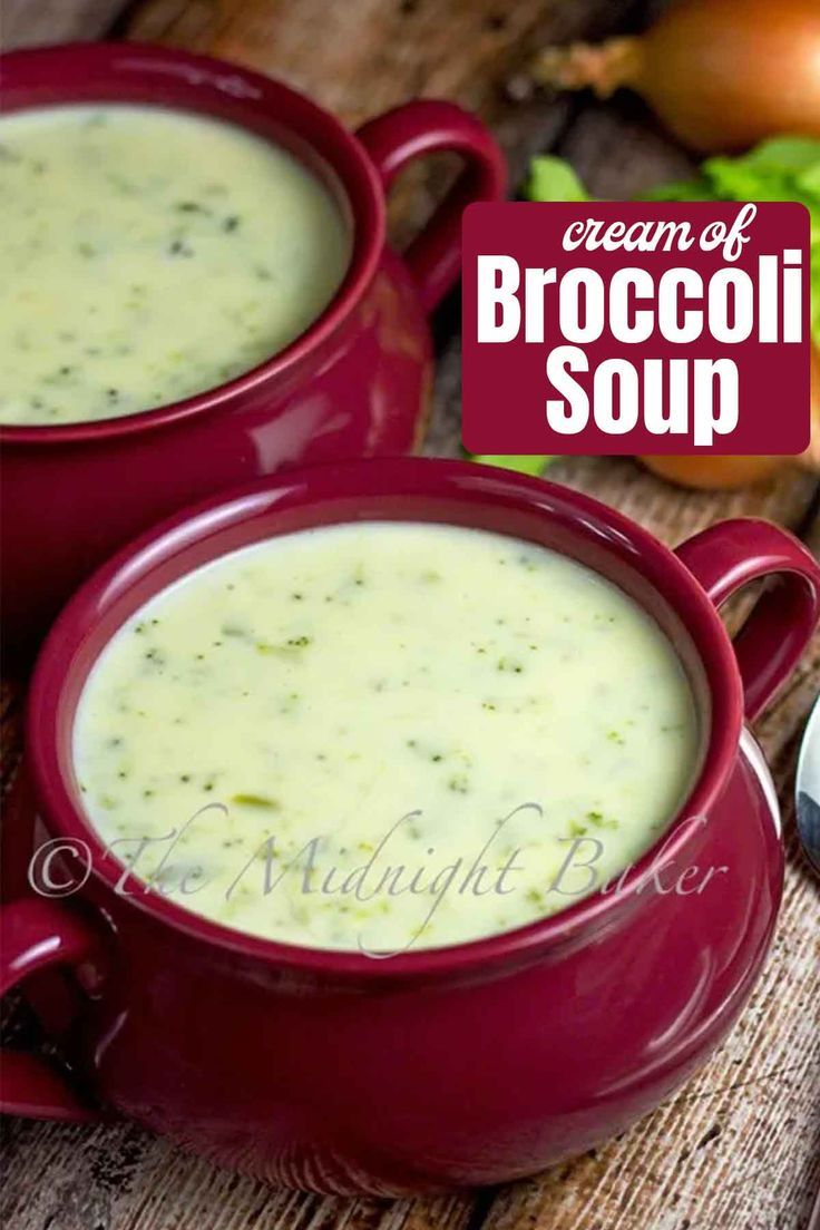 two red mugs filled with broccoli soup on top of a wooden table