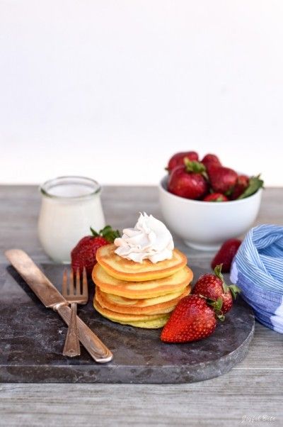 a stack of pancakes with whipped cream and strawberries next to it on a plate