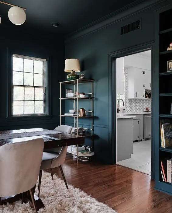 a dining room with dark green walls and wooden floors, along with a white sheepskin rug on the floor