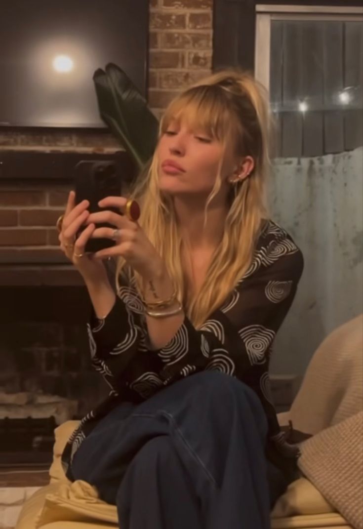 a woman sitting on a couch holding a cell phone