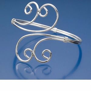 a silver cuff with two spirals on the end and one loop in the middle