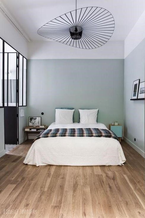 a bed sitting in the middle of a bedroom next to a wooden floor and window