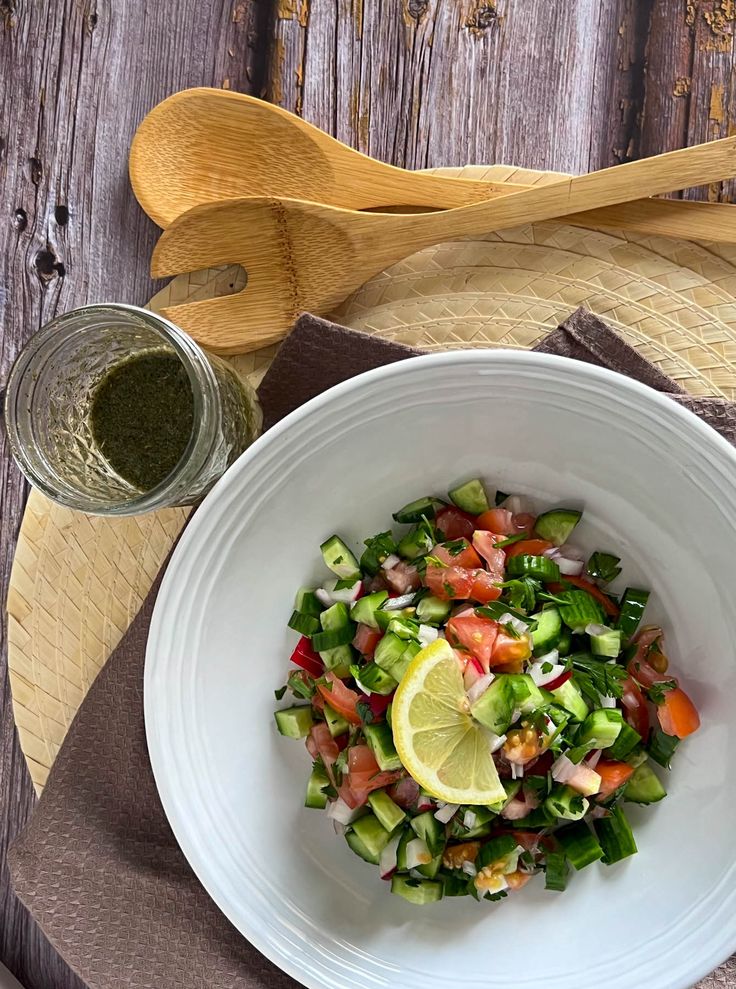 a white bowl filled with chopped vegetables next to a wooden spoon and knife on top of a cutting board