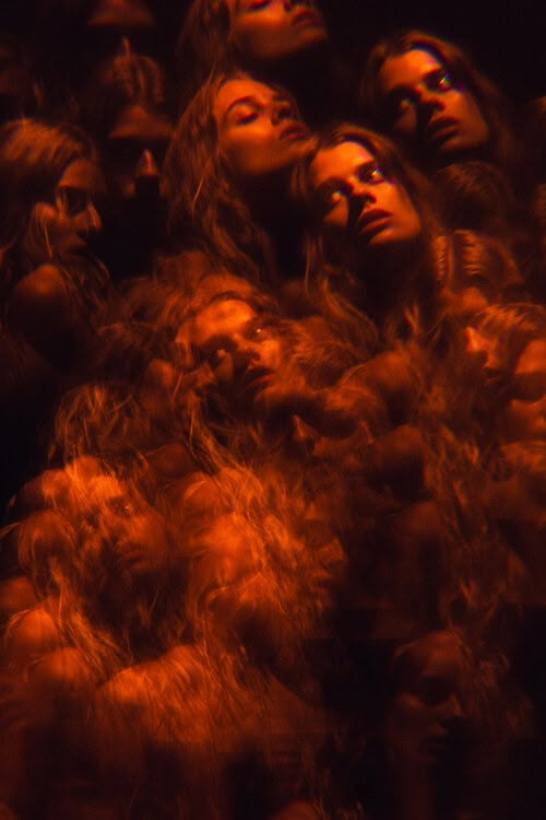 a group of people with long hair are looking up at the sky in red light