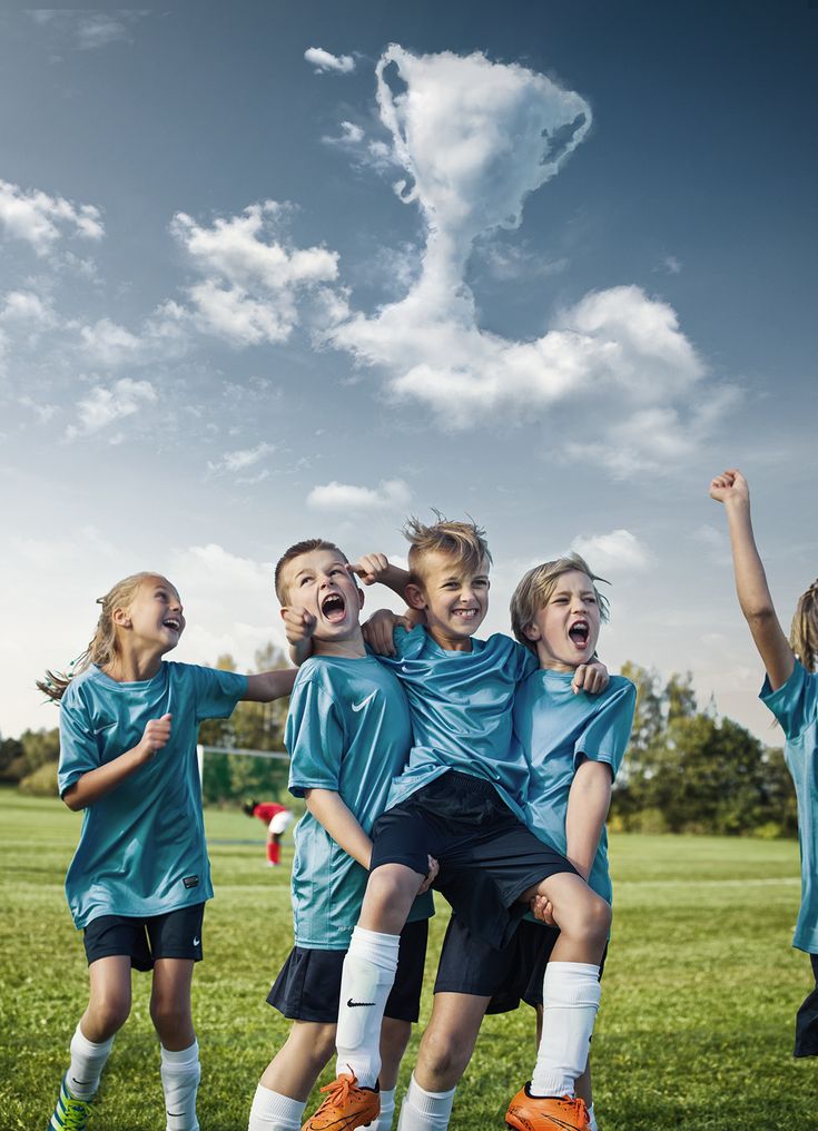 a group of young children standing next to each other on top of a green field