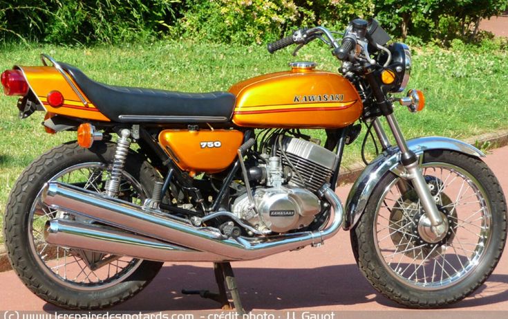 an orange and black motorcycle parked on the side of a road next to some grass