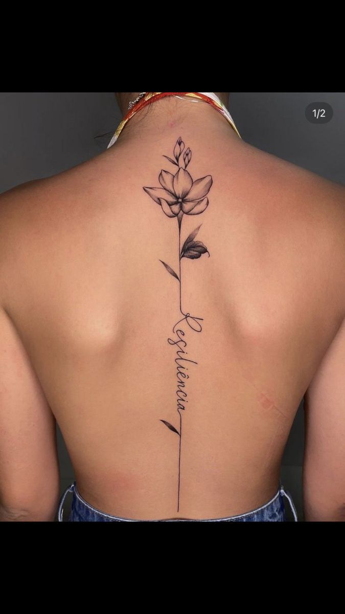 the back of a woman's neck with a flower tattoo on her left side