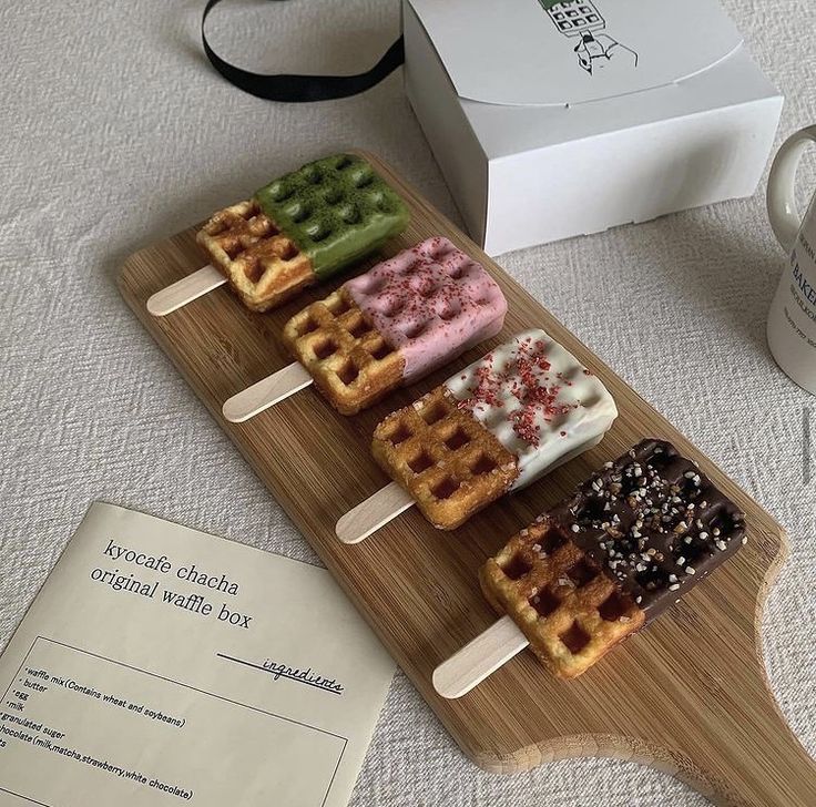 several waffles are on a wooden plate next to a coffee cup and box