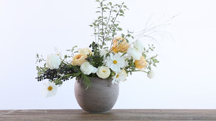 a vase filled with lots of white and yellow flowers