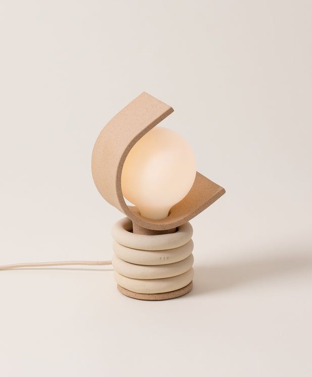 a small table lamp sitting on top of a stack of white discs with a light bulb plugged into it