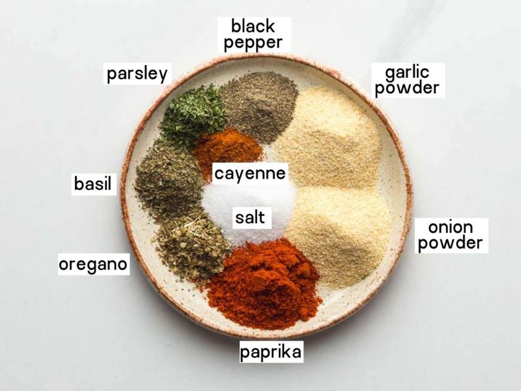 a bowl filled with spices labeled in different types of powders and seasonings on a white surface