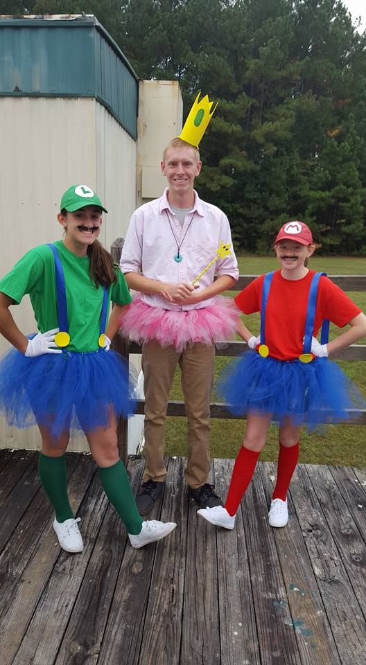 three people dressed in costumes standing on a wooden deck with one person wearing a crown