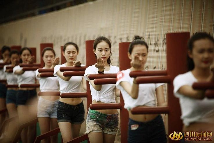 a group of young women standing next to each other in front of a wall with bars on it