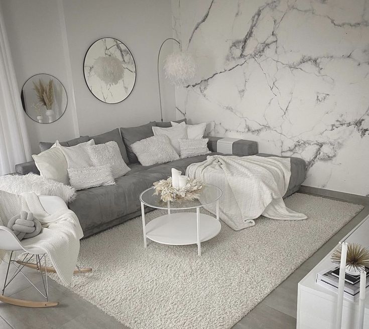 a living room filled with furniture and white rugs on top of a hard wood floor