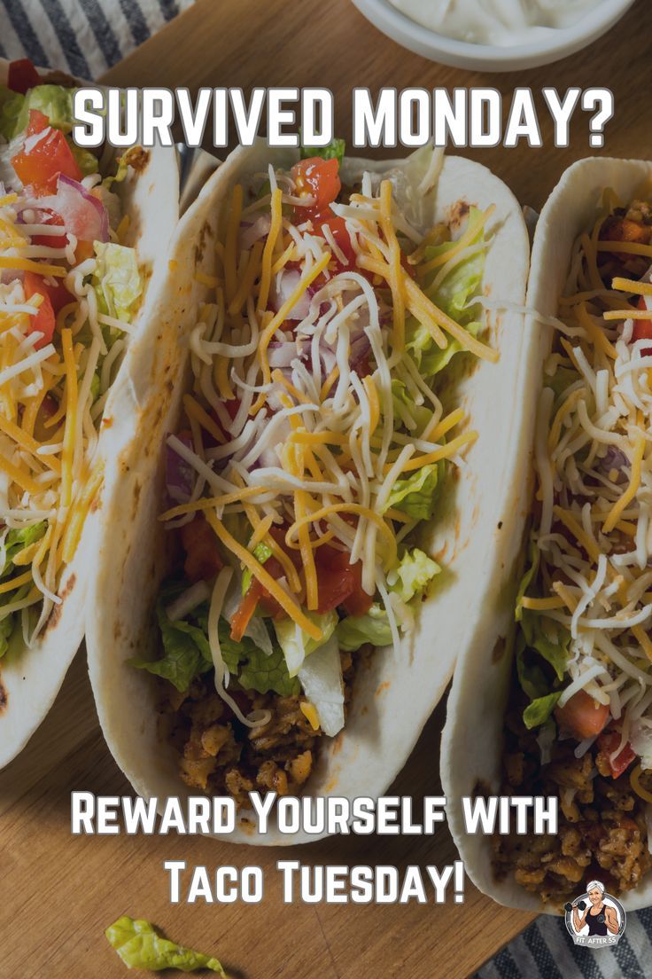 three tacos with shredded cheese and lettuce on them sitting on a table