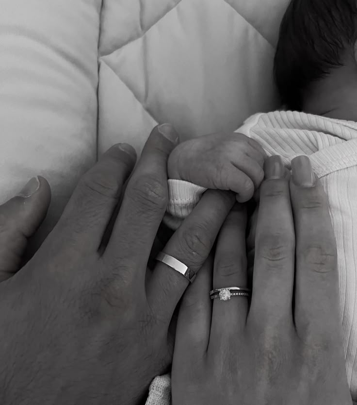 a man holding a baby in his arms while another person holds the baby's hand