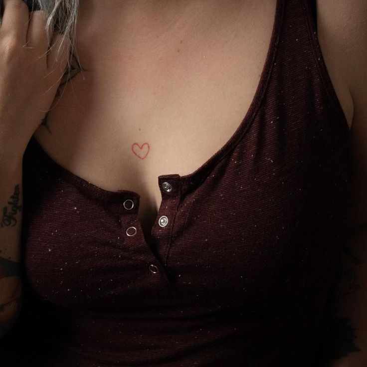 a woman with tattoos on her chest holding a cell phone