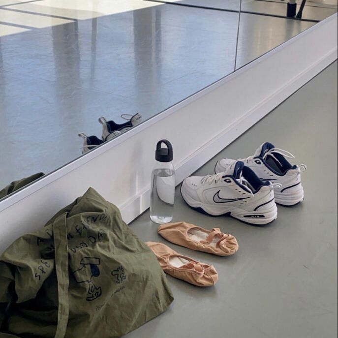 several pairs of shoes are sitting on the floor next to a bag and water bottle