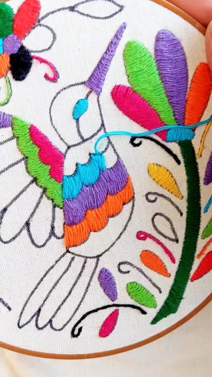 someone is stitching an embroidered design on a white piece of cloth with colorful thread