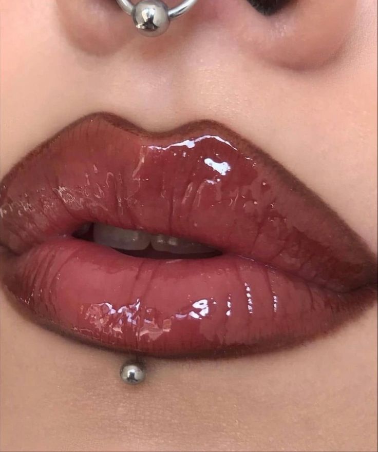 a woman's nose with piercings on it and her lips are shiny red