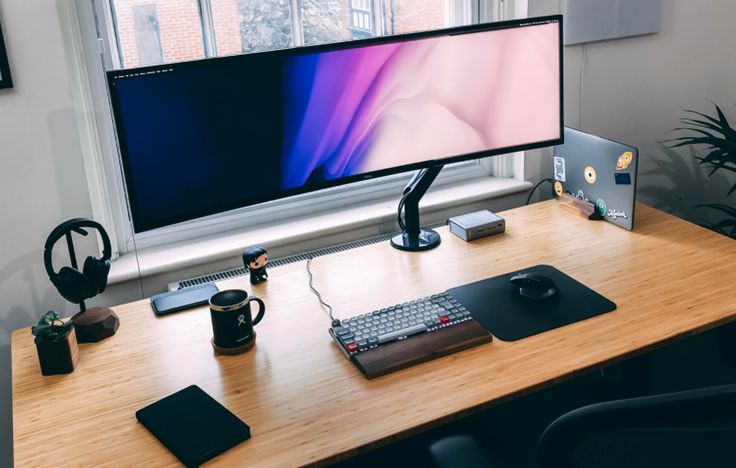 a computer monitor sitting on top of a wooden desk next to a keyboard and mouse