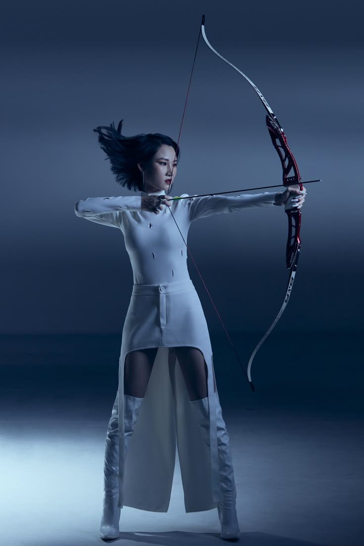 a woman dressed in white holding a bow and arrow