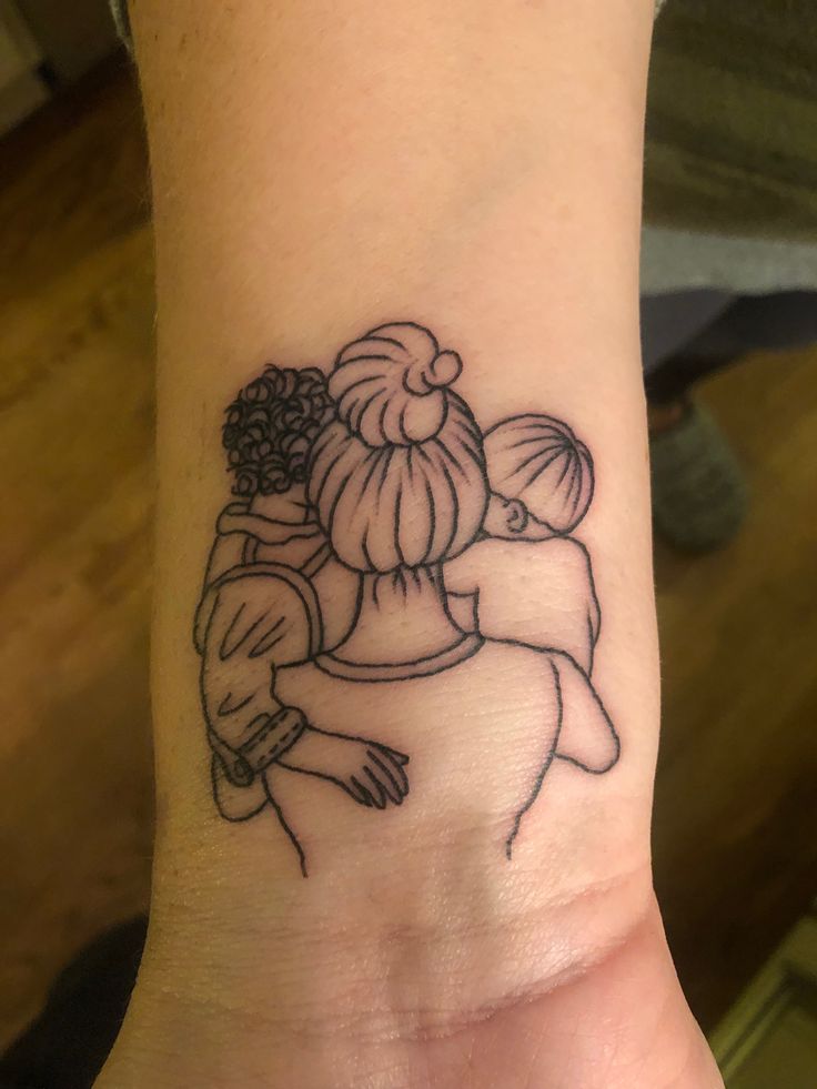 a woman's arm with a small tattoo of two women hugging each other on it