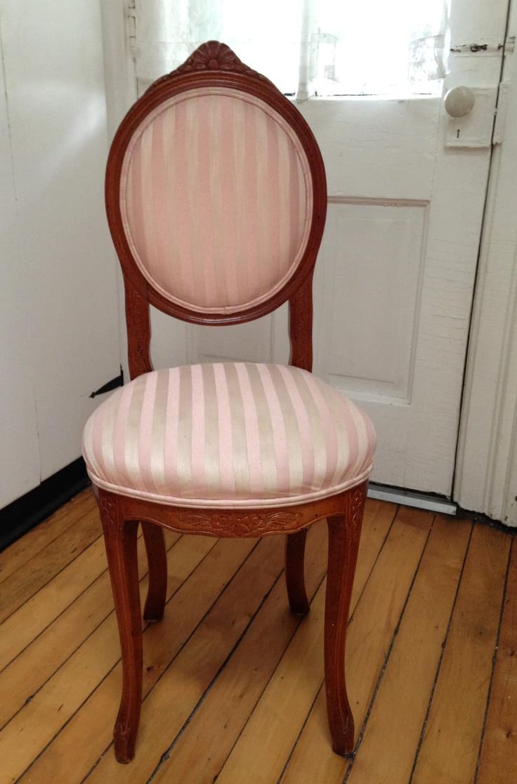 a pink and white striped chair sitting on top of a wooden floor next to a door