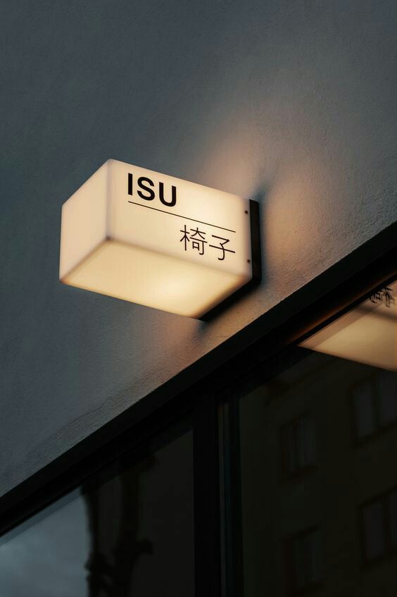 a close up of a light on the side of a building with chinese characters below it