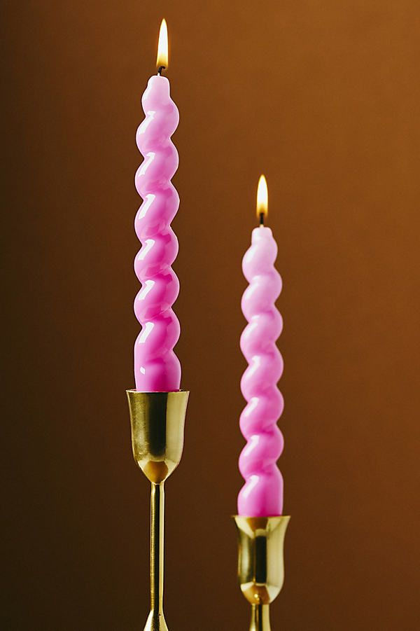 two pink candles are sitting on top of each other with one candle in the middle