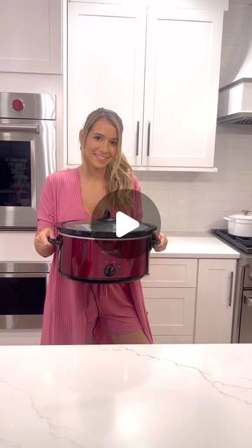 a woman is holding a large pot in her kitchen