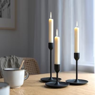 three candles are sitting on the table next to a cup