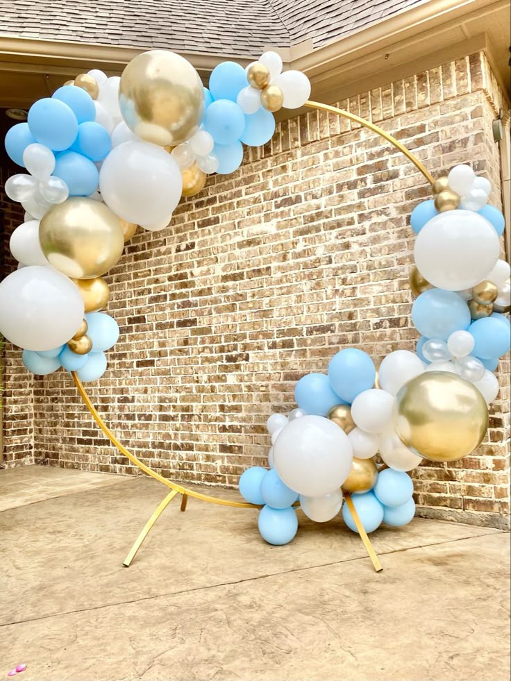 a balloon arch with blue, white and gold balloons