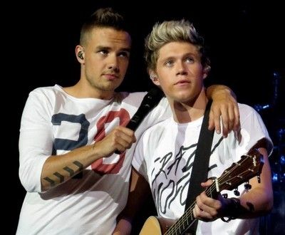 two young men standing next to each other holding guitars