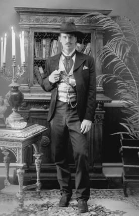 an old photo of a man standing in front of a table with candles on it