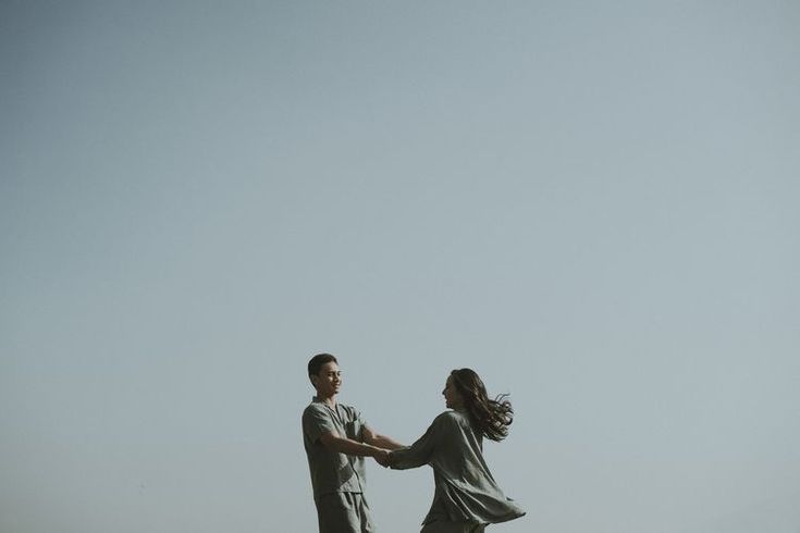 two people standing on top of a grass covered field