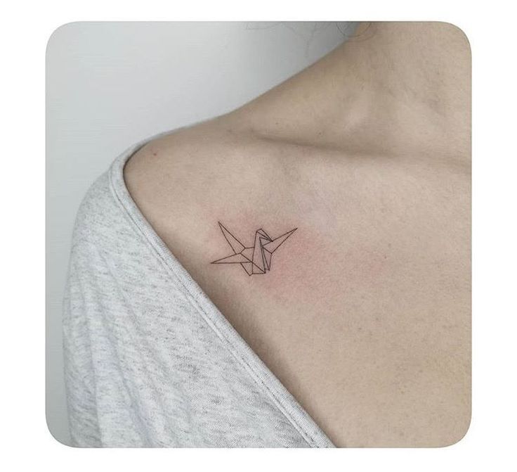 a woman's chest with a small origami bird tattoo on it