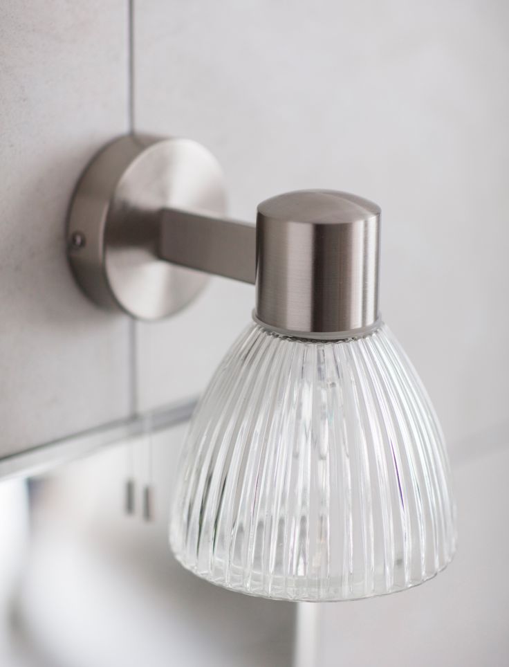 a light that is on the side of a wall mounted fixture with a glass shade