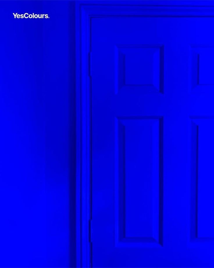 a blue door in a room with a black cat sitting on the floor next to it