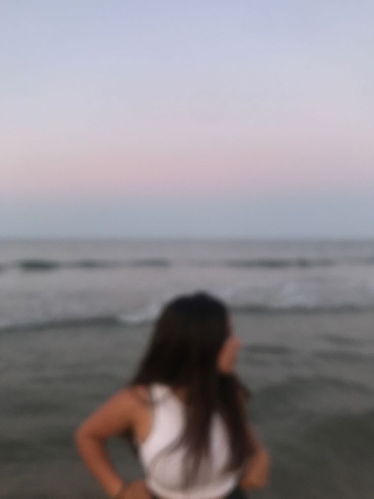 a woman standing on top of a beach next to the ocean