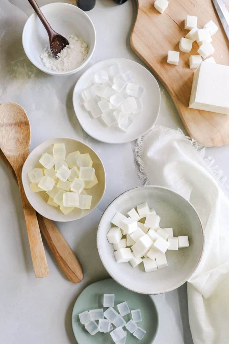 several bowls and spoons filled with sugar cubes on top of a white counter