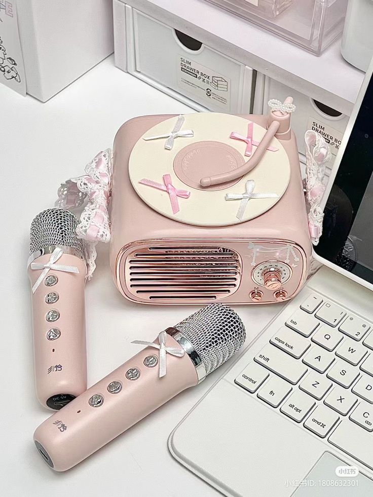 a pink radio sitting on top of a white desk next to a laptop and microphone