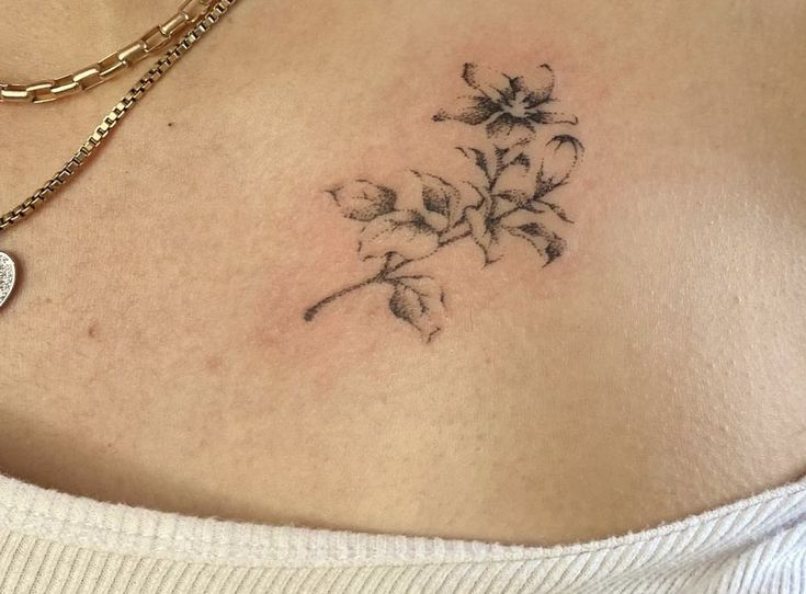 a close up of a woman's chest with flowers tattooed on the back of her stomach