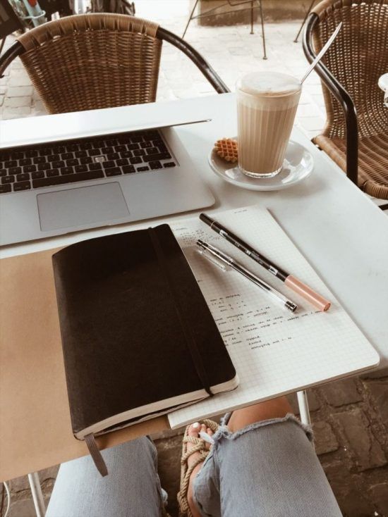 a laptop computer sitting on top of a white table next to a cup of coffee